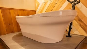 Une salle de bain moderne avec une baignoire sur pieds, des murs recouverts de panneaux en bois et un sol carrelé.