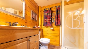 Un baño de madera con inodoro, lavamanos y espejo.