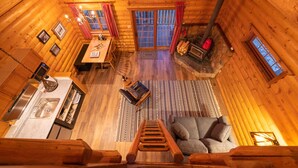 Een gezellig interieur van een blokhut met een eethoek, keuken en een open haard.