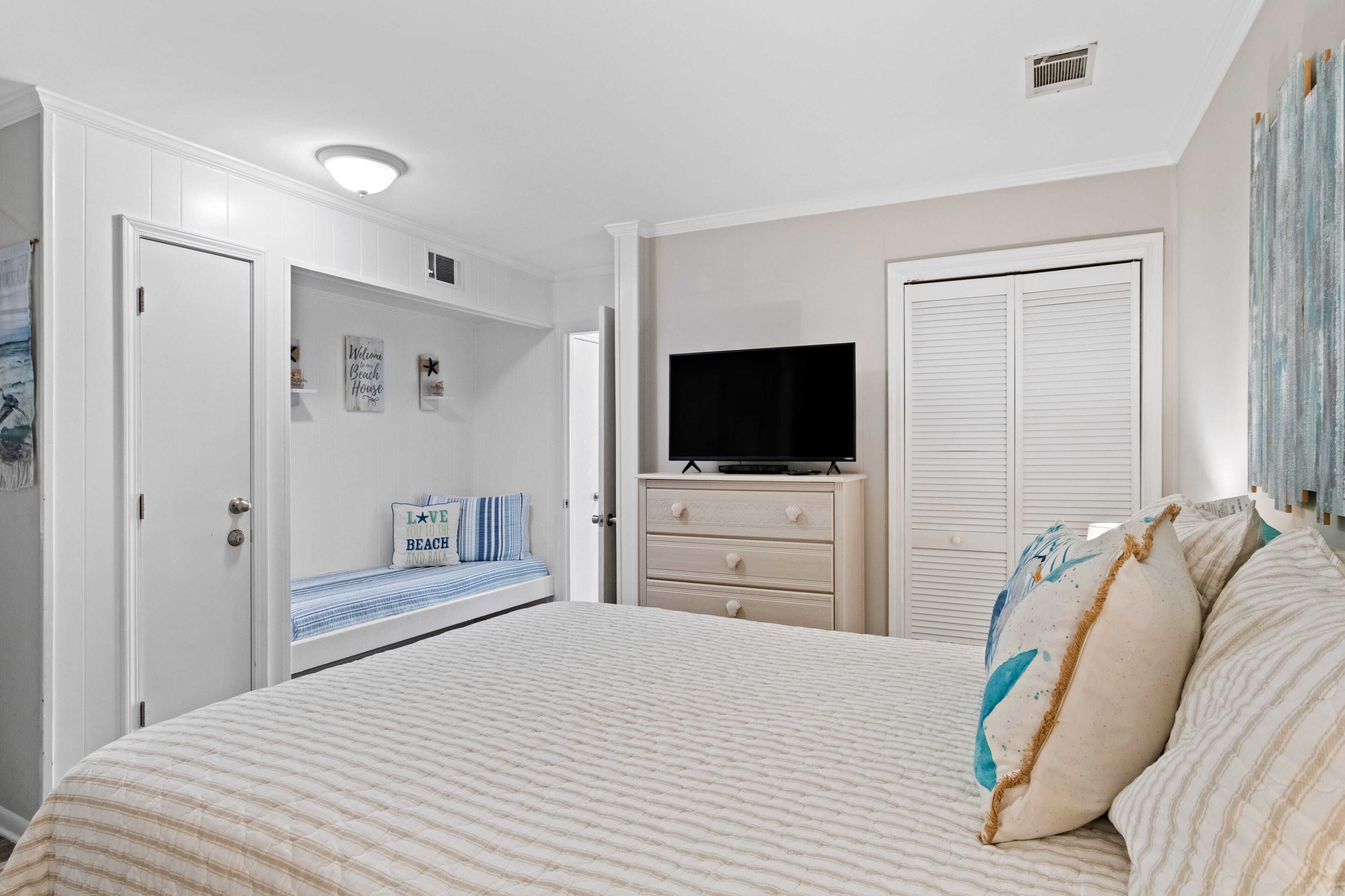 A bedroom with a bed, a dresser, a television, and a closet.