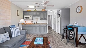 Un espacio habitable compacto con kitchenette, comedor y zona de estar con una mesa de centro.
