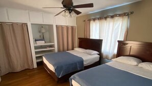Une chambre d’hôtel avec deux lits, un ventilateur de plafond, une armoire et une fenêtre avec des rideaux.
