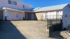 Un bâtiment à la façade rose et au toit gris, doté d’une cour intérieure et d’un petit escalier menant à un balcon.