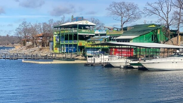 Un bâtiment situé au bord de l’eau, avec plusieurs étages, des bateaux amarrés et une vue dégagée sur l’eau.