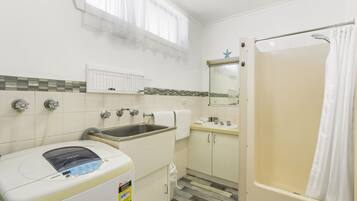 Een kleine badkamer met een wastafel, toilet en douche.