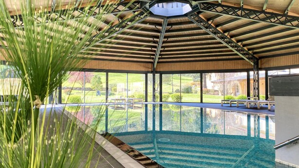 An indoor swimming pool with a view of a green landscape through large windows. - Beautiful apartment in Saint-Affrique with WiFi (Saint-Affrique)