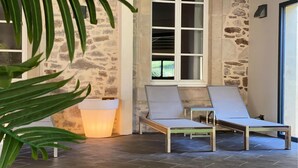 A room with two lounge chairs, a stone wall, a window, and a potted plant. - Beautiful apartment in Saint-Affrique with WiFi (Saint-Affrique)