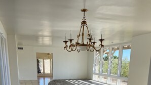 A spacious room with a large chandelier, large windows, and a tiled floor.