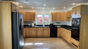 A modern kitchen with wooden cabinets, a black refrigerator, a dishwasher, and a stove.