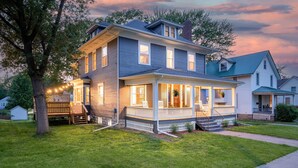 A two-story house with a porch, a deck, and a well-maintained lawn.