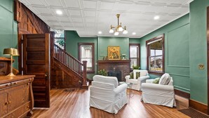 A spacious living room with a wooden staircase, a fireplace, and a green wall.