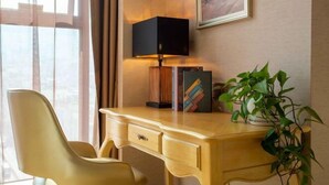 A hotel room with a wooden desk, a modern lamp, a bookshelf, and a potted plant. - Vienna International Hotel (Bijie Dafang Branch) (Bijie)