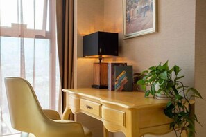 A hotel room with a wooden desk, a modern lamp, a bookshelf, and a potted plant. - Vienna International Hotel (Bijie Dafang Branch) (Bijie)