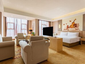 Una habitación de hotel con cama, televisión, escritorio y dos sillones.