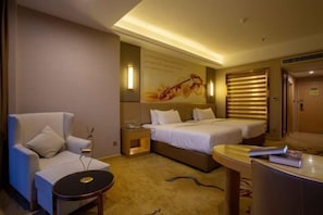 A hotel room with a sofa, two beds, a small table, and a wall-mounted artwork. - Vienna International Hotel (Bijie Dafang Branch) (Bijie)