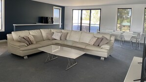 A modern living room with a sectional sofa, a coffee table, and a TV on a shelf. - 2 minutes to the Murray River large Family home<br> (Bundalong)