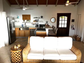 A modern kitchen with a dining area, including a wicker sofa and a small side table.