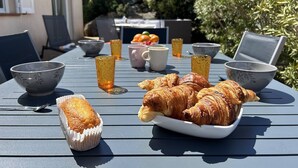 Ein Tisch im Freien mit Croissants, Schüsseln und Gläsern.