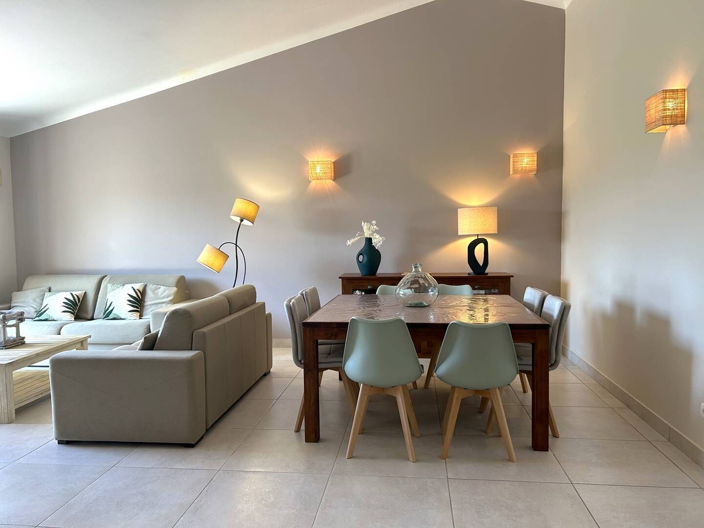 Un salon moderne comprenant un canapé, une table à manger avec des chaises et deux lampadaires.