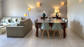 Ein modernes Wohnzimmer mit einer Couch, einem Esstisch mit Stühlen und zwei Stehlampen.