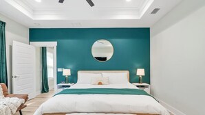 A bedroom with a bed, two bedside tables, a mirror, and a door. - • Emerald-Gem-Inn • PCB • Family Fun Beach Home! • (Panama City Beach)