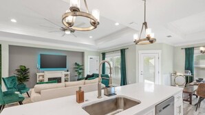 A modern kitchen with a central island, stainless steel appliances, and a dining area with a table and chairs. - • Emerald-Gem-Inn • PCB • Family Fun Beach Home! • (Panama City Beach)