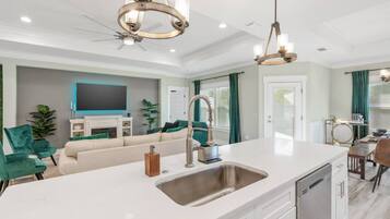A modern kitchen with a central island, stainless steel appliances, and a dining area with a table and chairs.