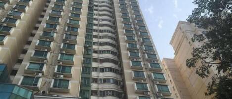 Un edificio de gran altura con varios balcones y una serie de locales comerciales en la planta baja.