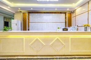 A reception desk with a marble top, a gold accent wall, and a small plant on the left. - Jinkuihua Hotel (Shenzhen Futian Port) (Shenzhen)