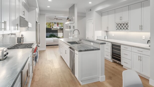 Una cocina moderna con armarios blancos, electrodomésticos de acero inoxidable y una isla central.
