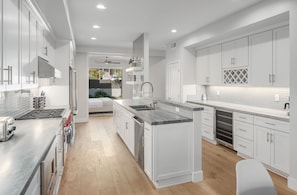 Een moderne keuken met witte kasten, roestvrijstalen apparatuur en een centraal eiland.