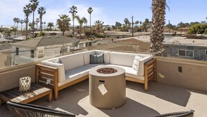 Una terraza en la azotea con un sofá modular, una mesa redonda y una silla.