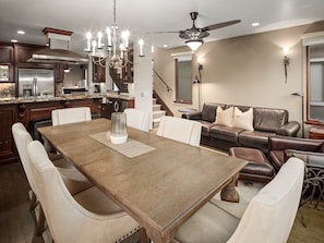 A spacious living room with a large wooden dining table, leather sofas, and a ceiling fan. - Ocean View Beach Home w/ AC, Outdoor Shower, Walk to PB (San Diego)