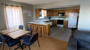 Een kleine woonruimte met een eethoek, kitchenette en een slaapbank.