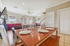Un vaste espace dédié à la salle à manger, avec une longue table en bois dressée pour quatre personnes, entourée de chaises.