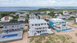 A coastal residential area with houses, a large blue building with a pool, and a beach in the background.