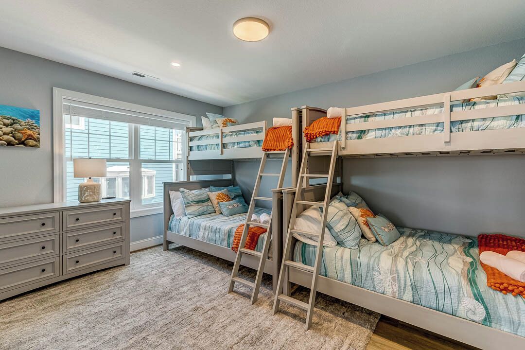 Een slaapkamer met stapelbedden, een dressoir, een raam en een ladder.