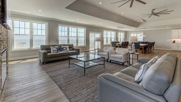 A spacious living room with a large window, a ceiling fan, and a dining area.
