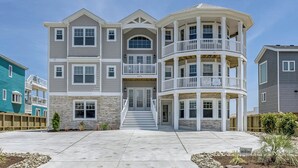 A multi-story residential building with a central entrance, a curved balcony, and a stone facade.