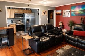 A modern living room with a black leather sofa, a wooden coffee table, and a kitchen area with stainless steel appliances. - Modern High-Floor condo at Heart of Downtown & Skyline Balcony (Atlanta)