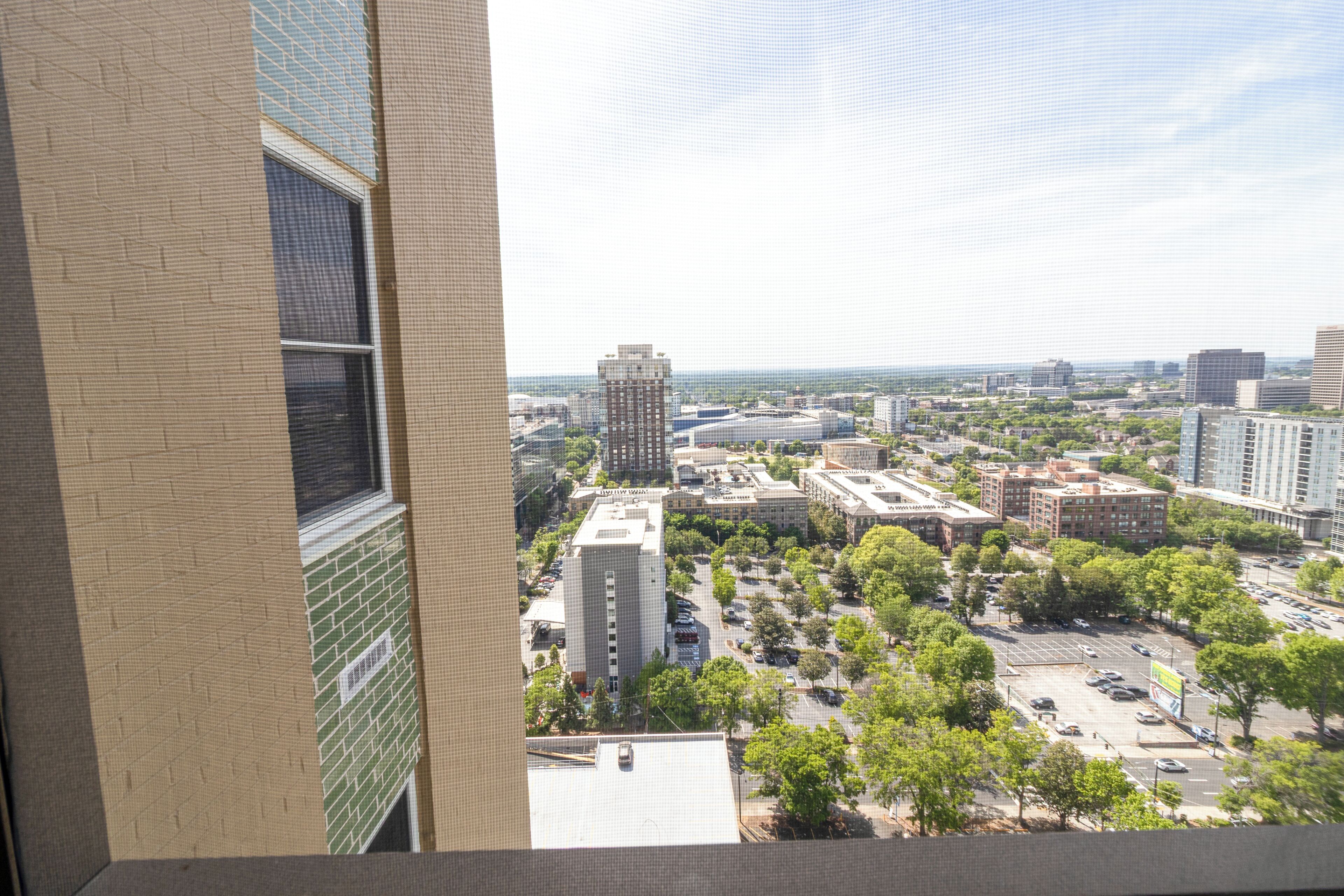 Une vue panoramique sur la ville, prise depuis un immeuble de grande hauteur, avec de nombreux bâtiments, des routes et des espaces verts.