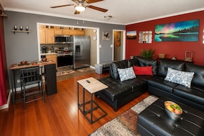 A modern living room with a black leather sofa, a wooden coffee table, and a kitchen in the background. - Modern High-Floor condo at Heart of Downtown & Skyline Balcony (Atlanta)