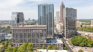 A high-rise building with a modern glass facade, surrounded by other buildings and greenery. - Modern High-Floor condo at Heart of Downtown & Skyline Balcony (Atlanta)