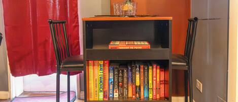 A bookshelf with books, a vase with flowers, and two chairs.