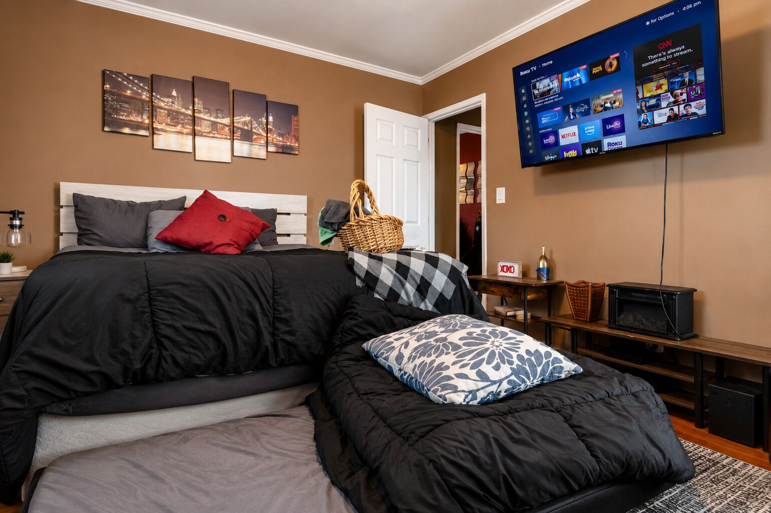 A bedroom with a bed, a TV mounted on the wall, and a window.