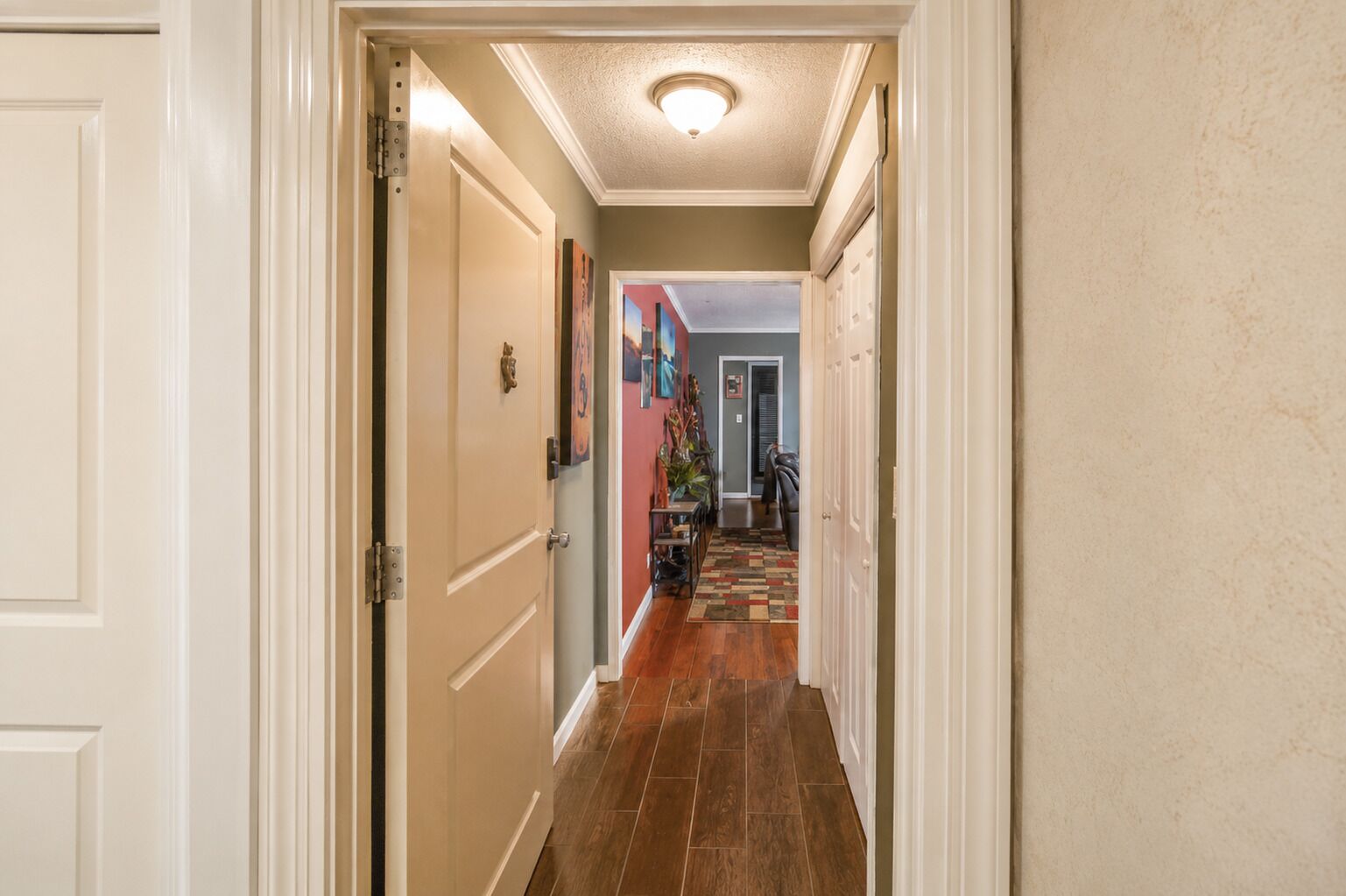 A hallway with wooden flooring, white doors, and a ceiling light fixture.