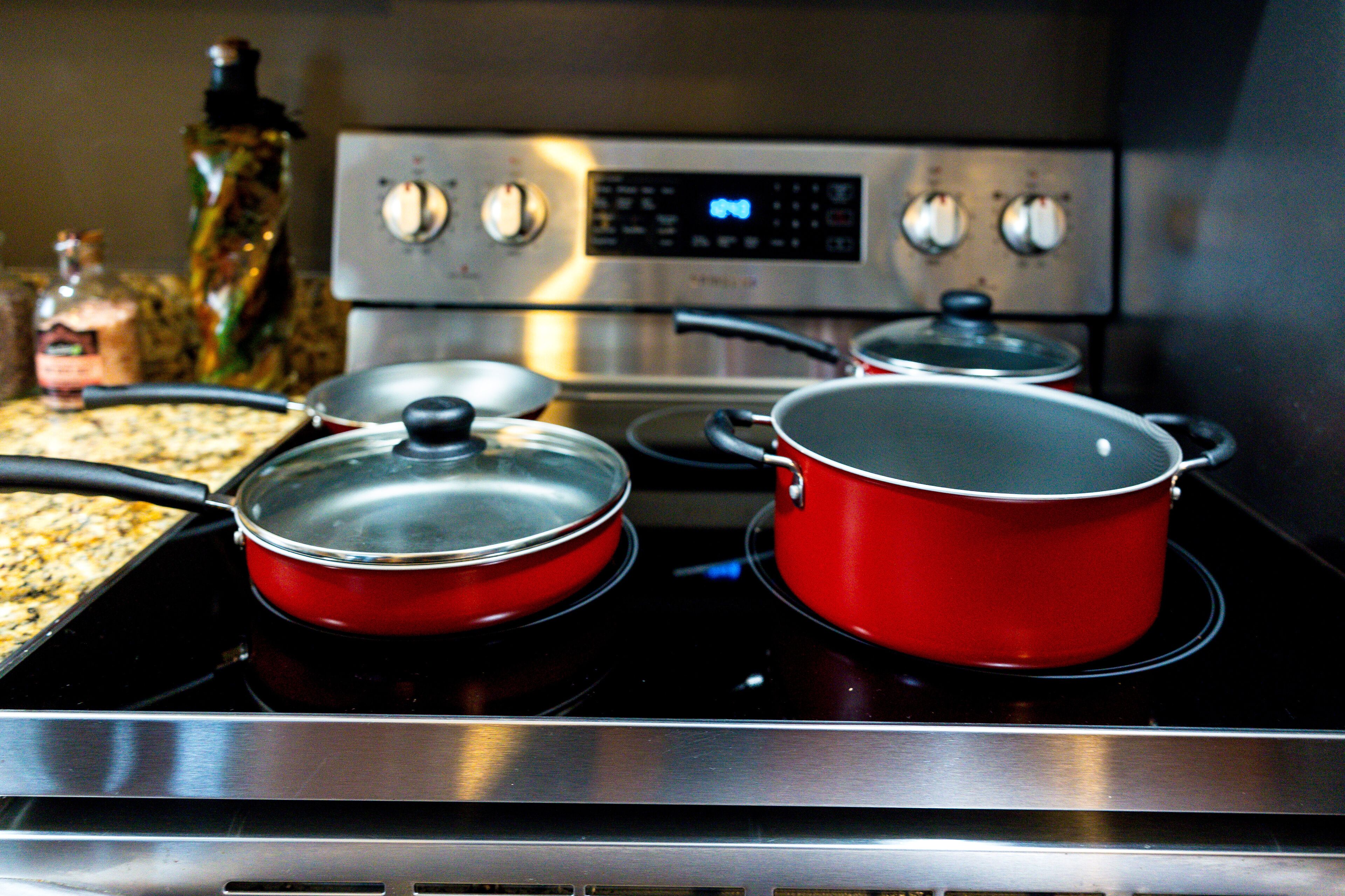 A kitchen with a stove, pots, and a digital clock.
