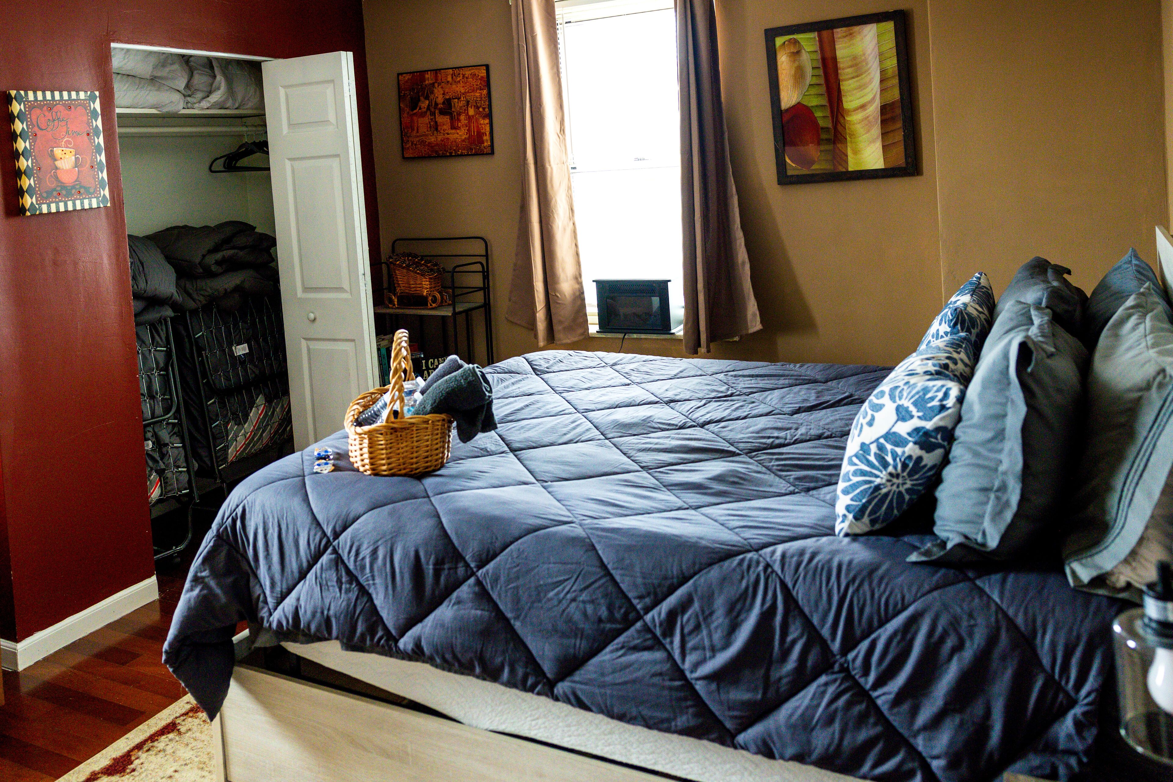 A bedroom with a large bed, a wardrobe, a desk, and a window with curtains.