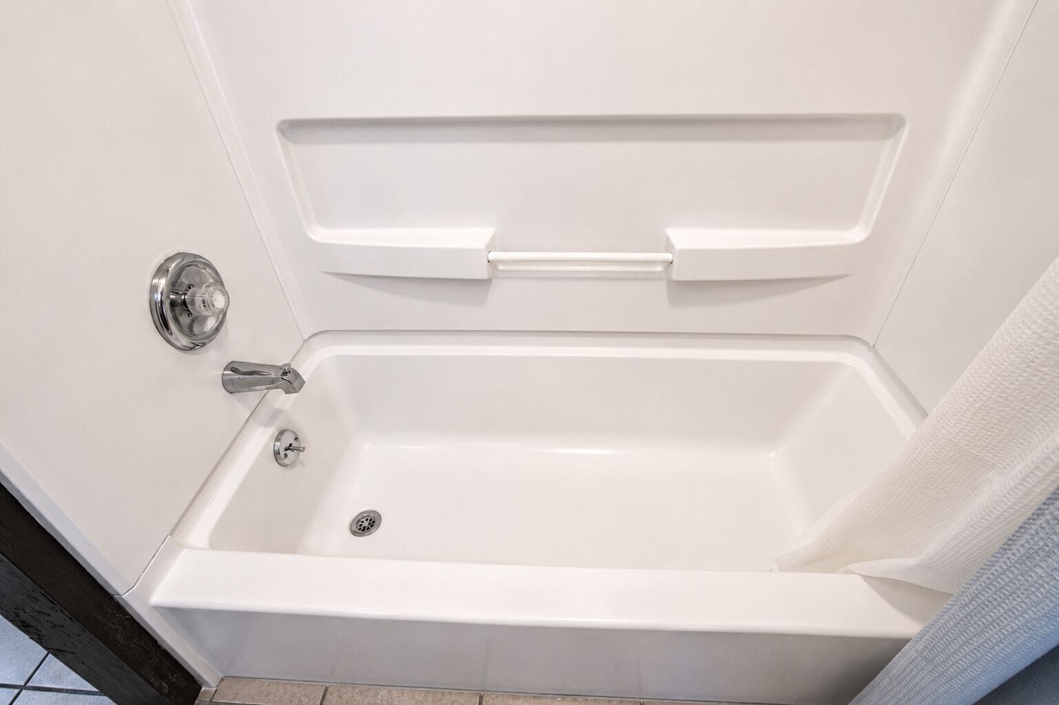 A white bathtub with a chrome faucet and a drain.