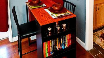 Un coin repas avec une table en bois, des chaises et une bibliothèque remplie de livres.
